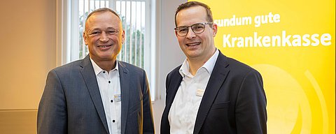 Zwei Männer in Geschädtskleidung schauen lächelnd in die Kamera.