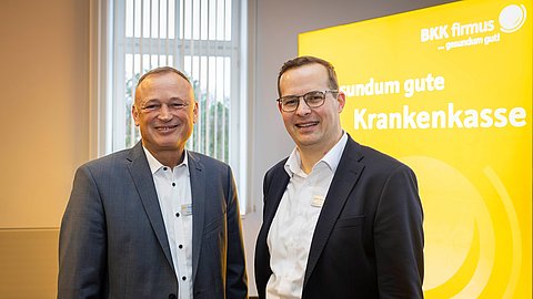 Zwei Männer in Geschädtskleidung schauen lächelnd in die Kamera
