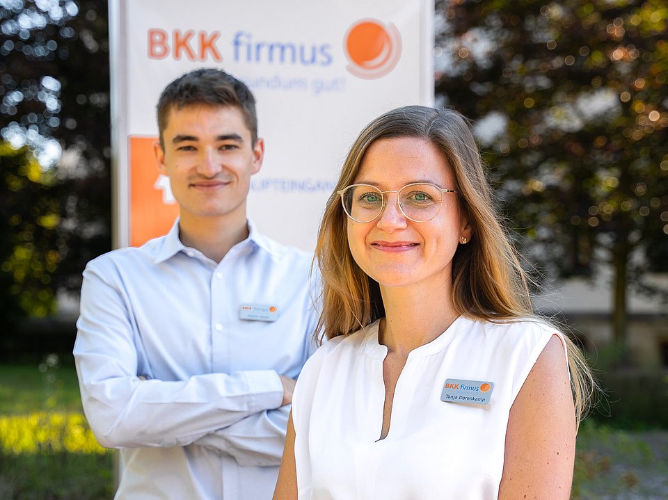 Zwei Mitarbeitende vor dem Gebäude der BKK firmus