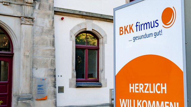 Ein Schild der Krankenkasse „BKK firmus“ heißt Besucher vor dem Servicezentrum in Osnabrück willkommen.