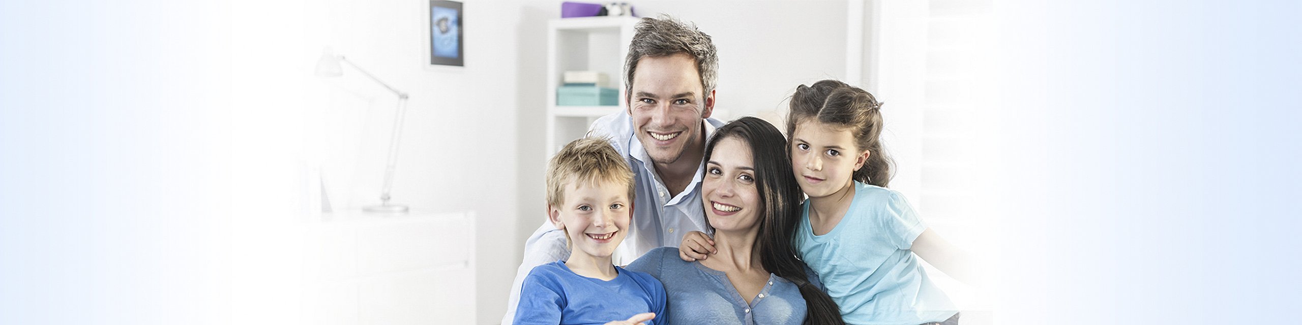 Fröhliche Familie mit zwei Erwachsenen und zwei Kindern, die zusammen in einem hellen Raum stehen