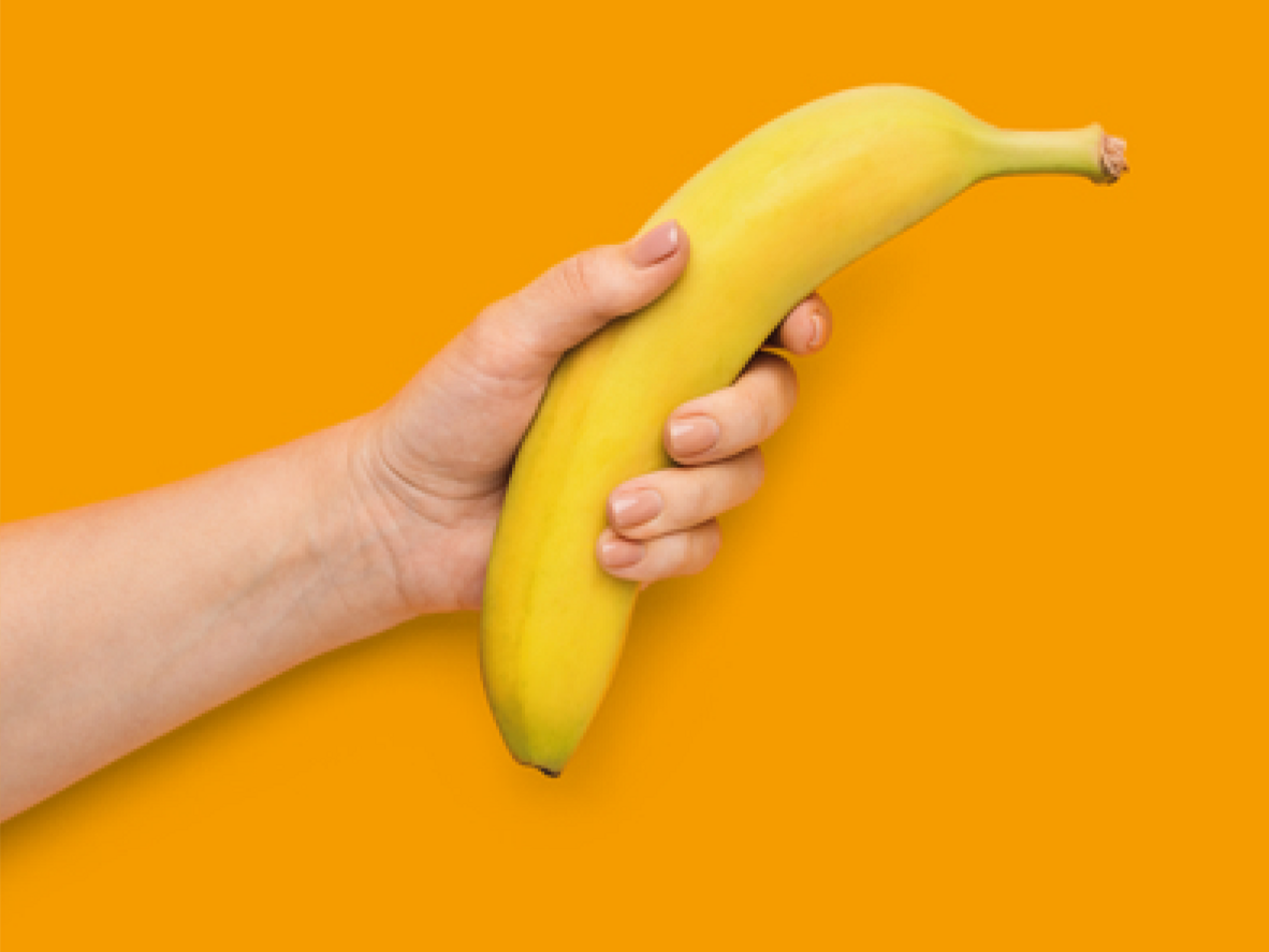 Hand hält Banane vor orangefarbenem Hintergrund mit Text zu Gesundheitsvorteilen und Ersparnis bei BKK firmus.