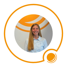 Eine lächelnde Frau mit langen blonden Haaren und einem hellblauen Hemd steht vor einem weiß-orangenen Hintergrund.