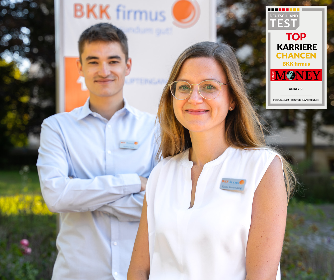Focus Money Top Karrierechancen 2024 Zwei lächelnde Fachleute in BKK firmus-Uniformen stehen im Freien; in der Ecke ist ein Preisabzeichen zu sehen.